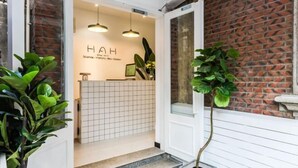 Zona de recepción con pared de azulejos, un mostrador y una planta en maceta.