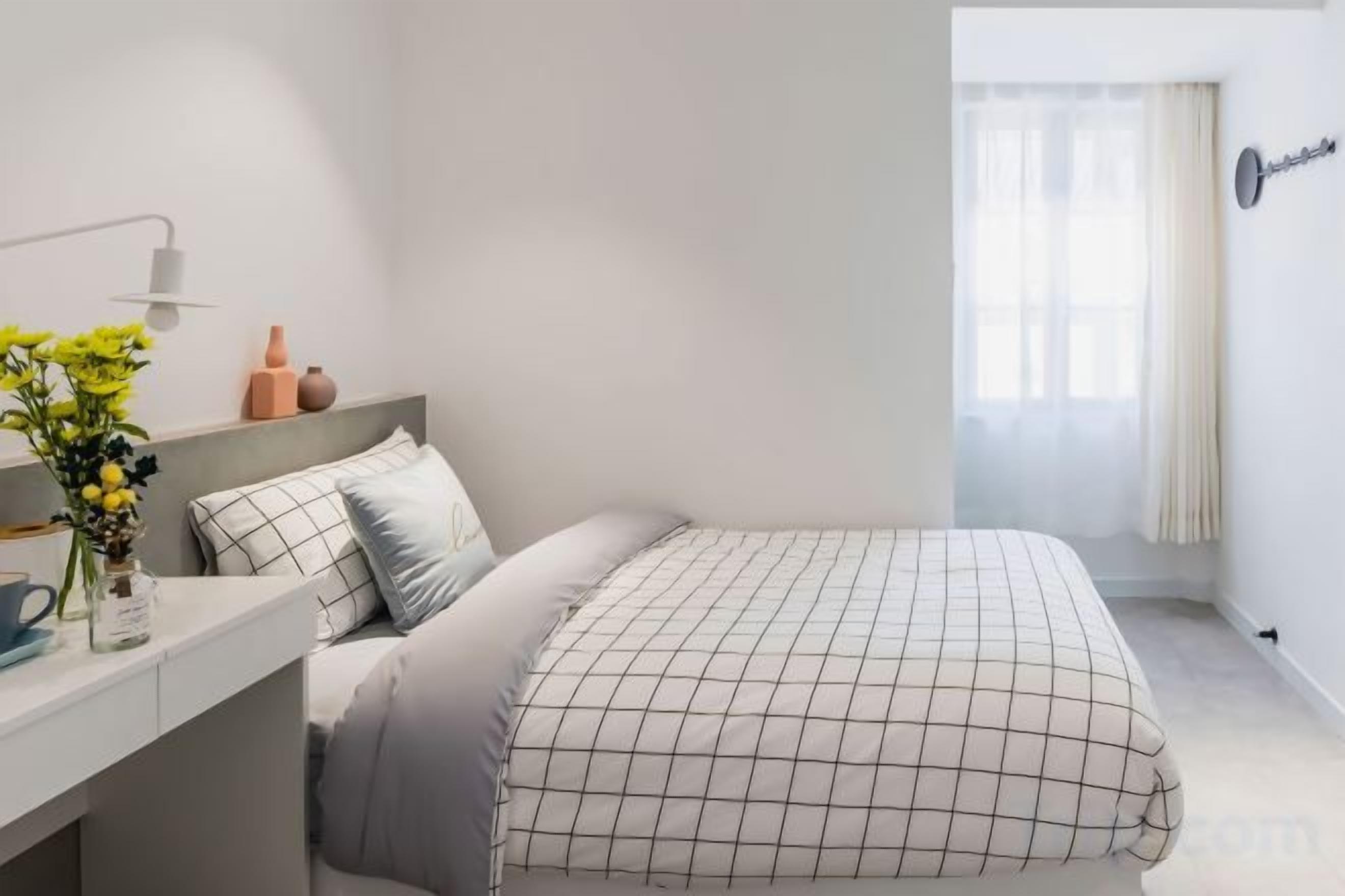 Une chambre à coucher avec un lit, une table de chevet, une lampe et une fenêtre avec des rideaux.
