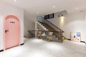 A staircase with a black railing leading to an upper floor, a pink door on the left, and a hexagonal tiled floor. - Gulangyu Hai'anhua Hotel (Xiamen)