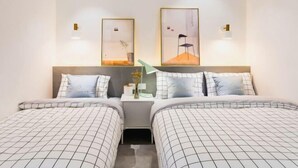 Una habitación de hotel con dos camas, una mesita de noche y lámparas fijadas a la pared.