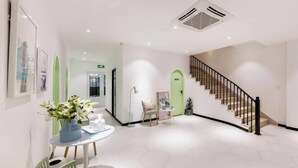 Un moderno vestíbulo de hotel con una escalera, una recepción y una zona de estar.