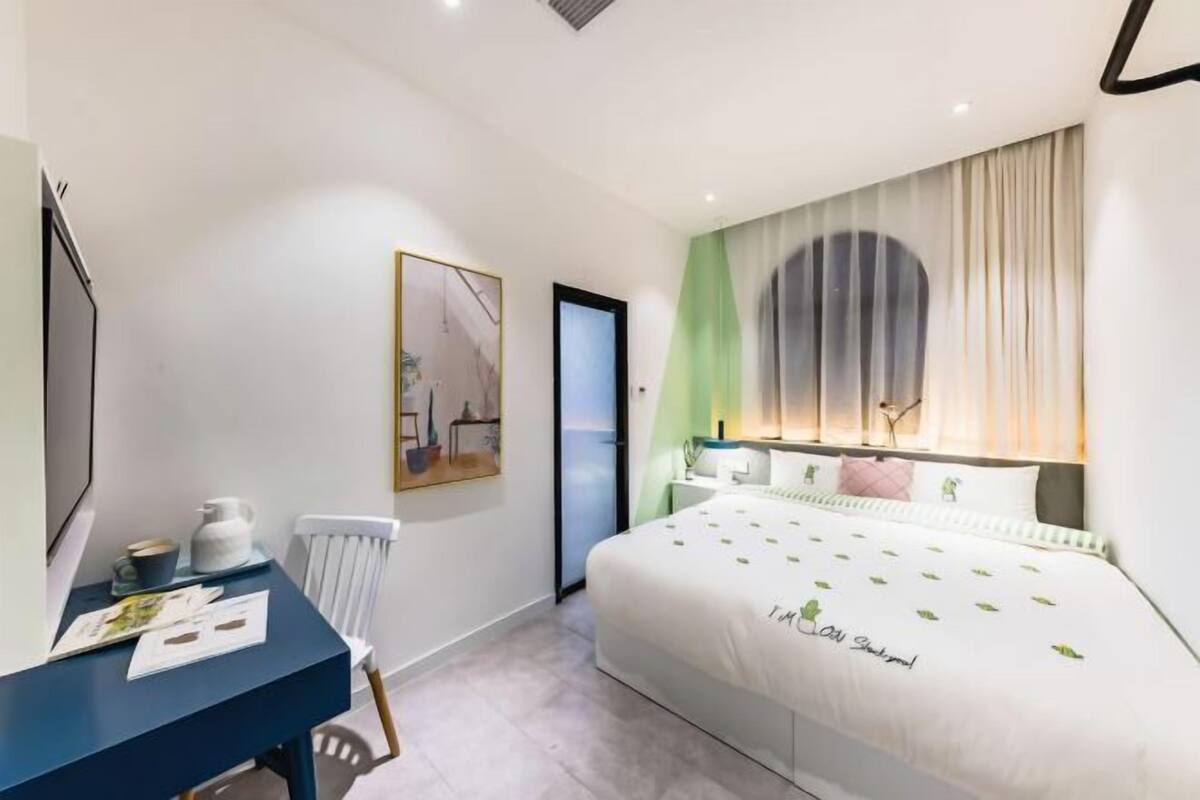 A modern hotel room with a bed, a desk, and a chair.