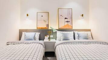 A hotel room with two beds, a nightstand, and wall-mounted lamps.