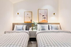 A hotel room with two beds, a nightstand, and wall-mounted lamps. - Gulangyu Hai'anhua Hotel (Xiamen)