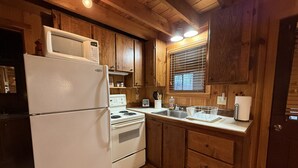 A compact kitchen with wooden cabinets, a white refrigerator, a stove, and a sink. - Cabin, Hot Tub, Forest View, Close to Town (West Jefferson)