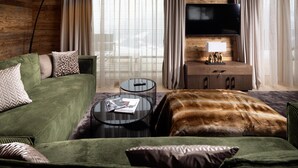 A cozy room with a green sofa, a round coffee table, a flat-screen TV, and a wooden cabinet.