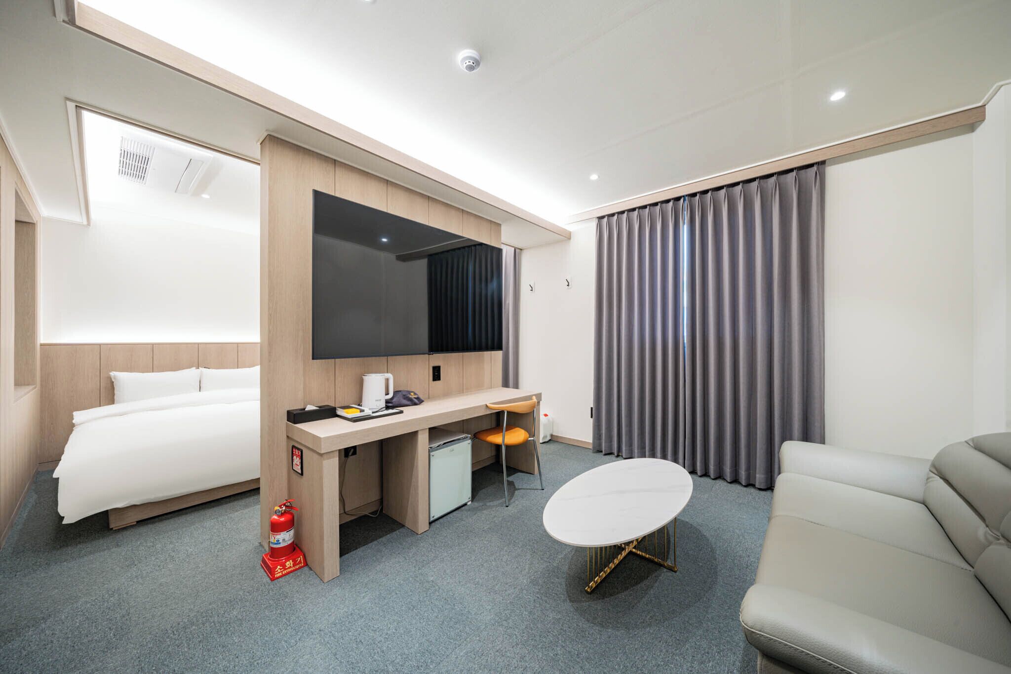 Una habitación de hotel moderna con cama, escritorio, silla, sofá y televisor.
