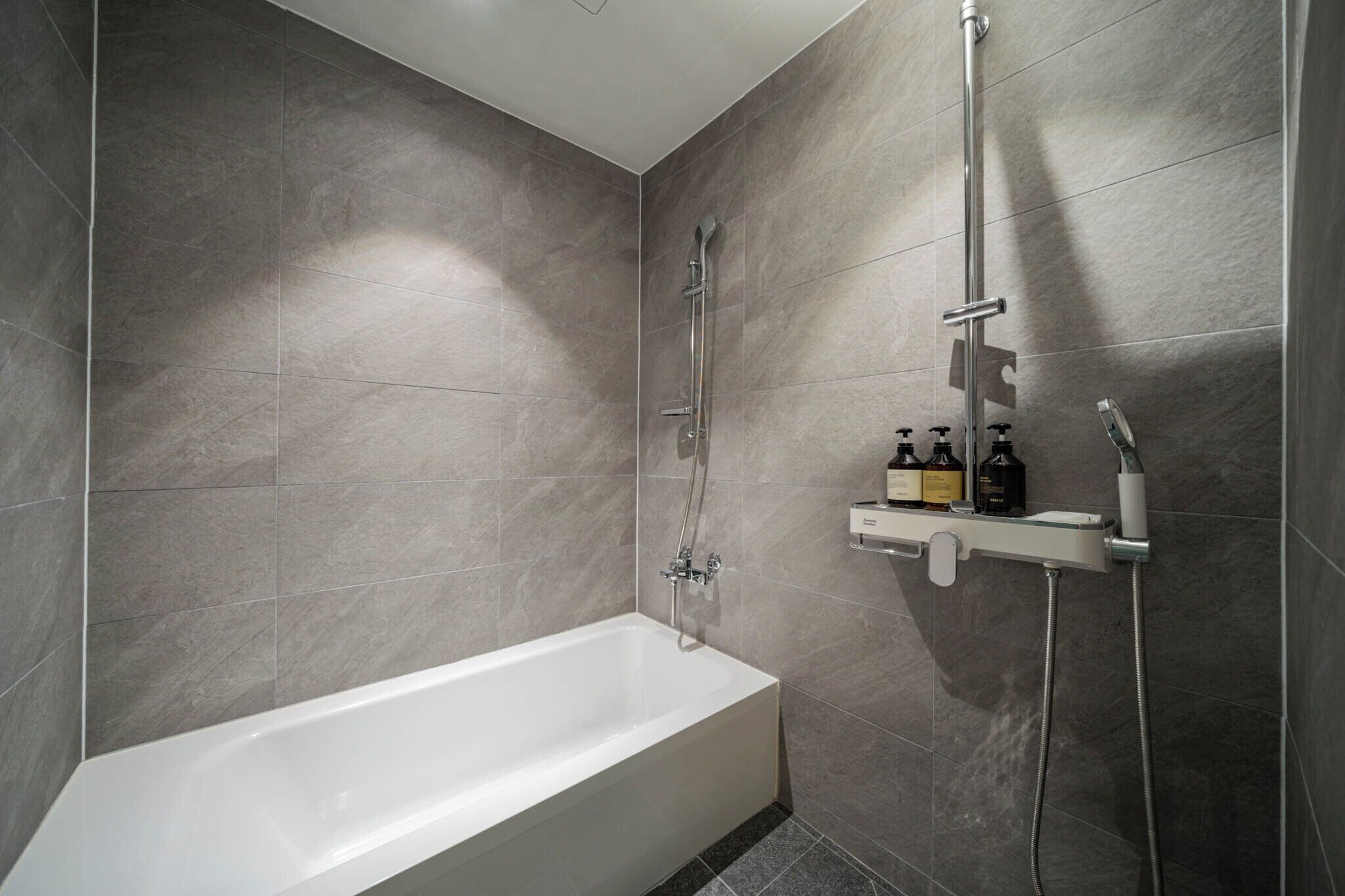 Un baño moderno con bañera, ducha y estante con artículos de aseo.