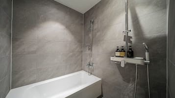 Un baño moderno con bañera, ducha y estante con artículos de aseo.