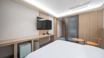 A modern hotel room with a large bed, a desk, a chair, a TV, and a sliding door.