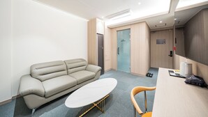Una habitación de hotel moderna con sofá, una mesita, un escritorio y una silla.