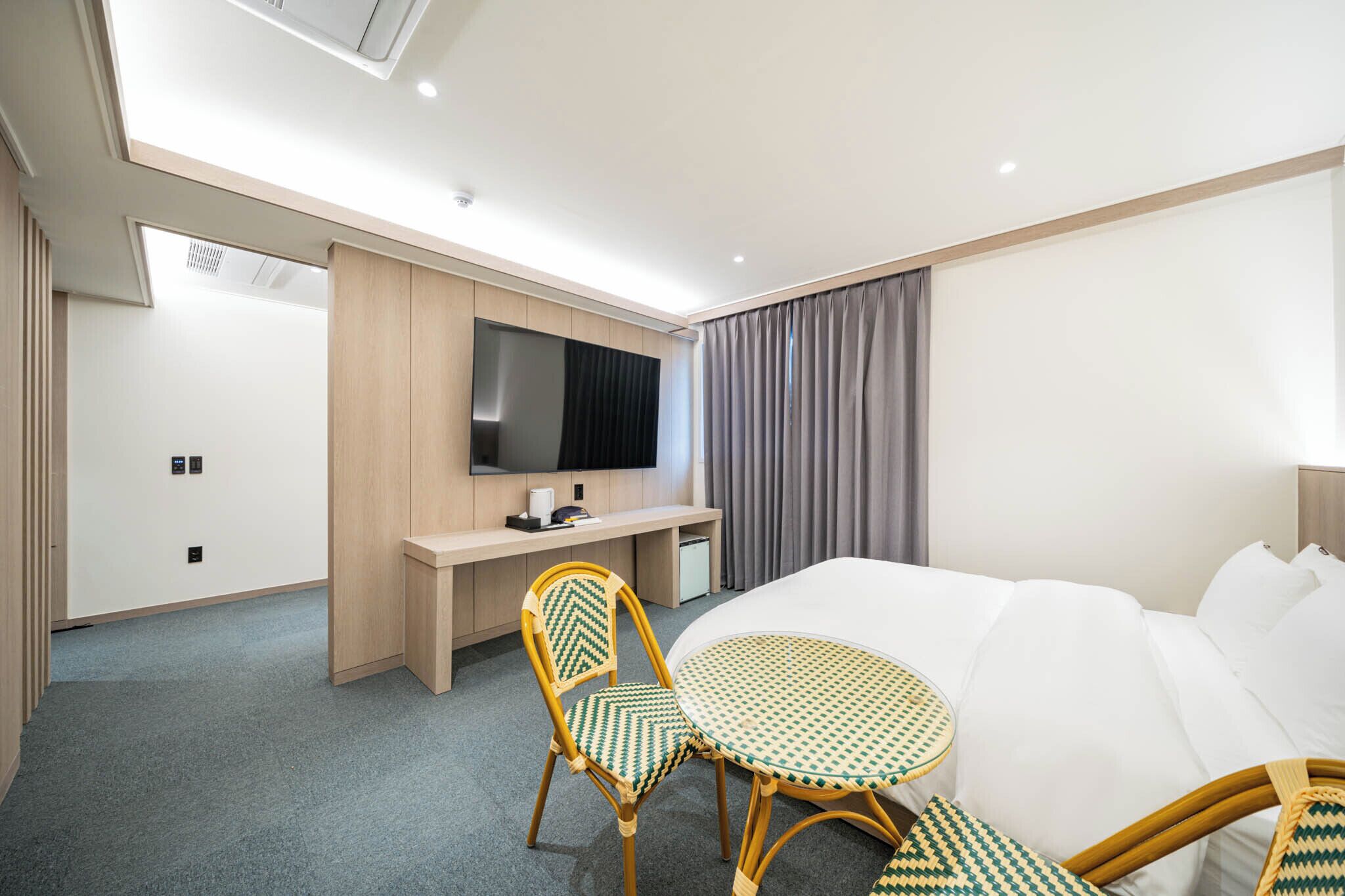 A hotel room with a bed, a desk, a television, a chair, and a small table.