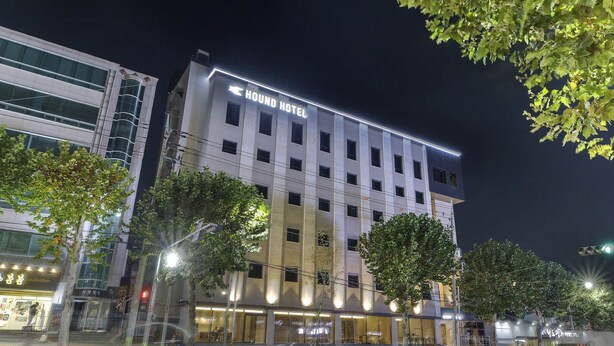 Un moderno edificio de hotel con un cartel llamativo, varios pisos y una fachada bien iluminada.