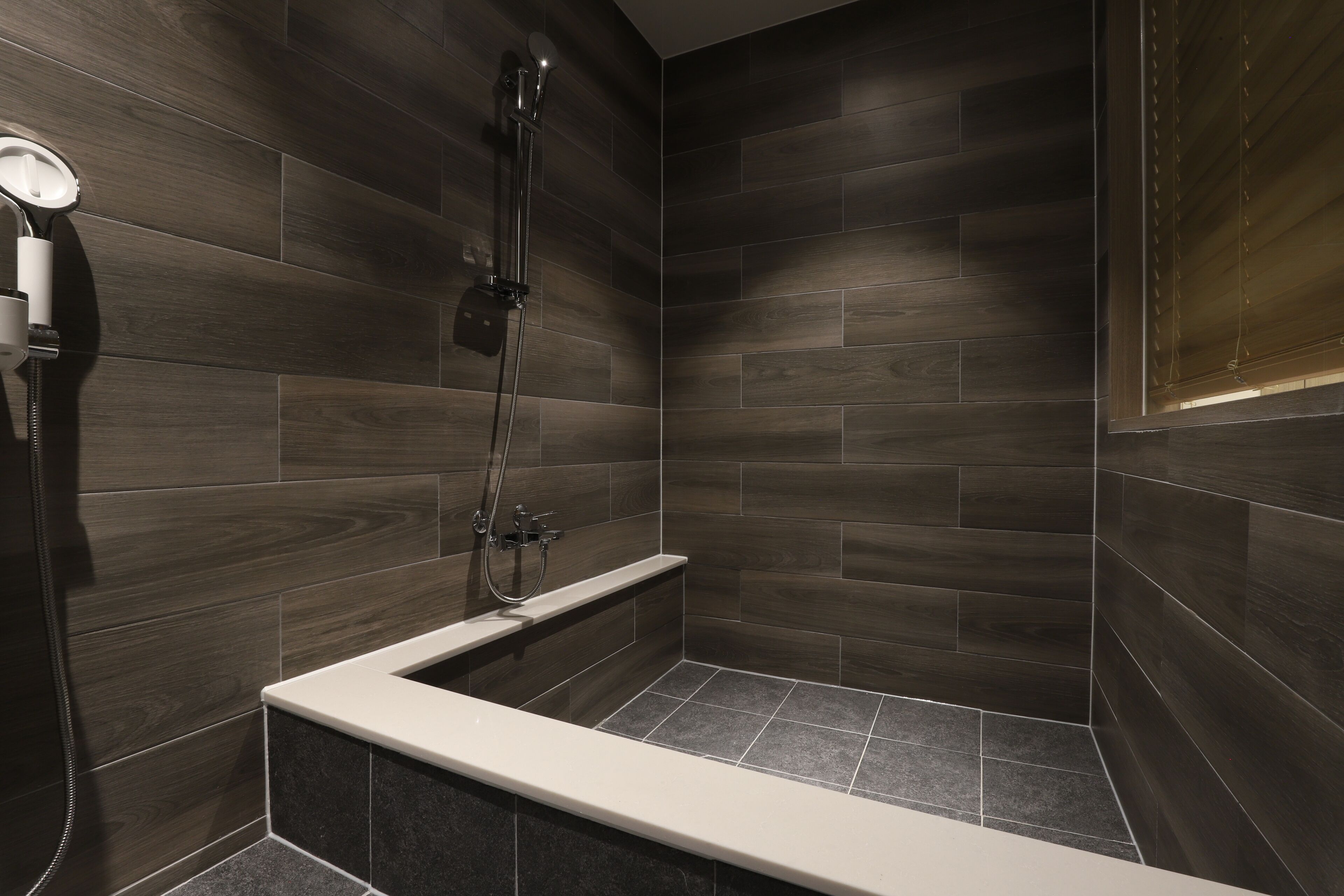 A modern shower area with a built-in bench and a handheld showerhead.