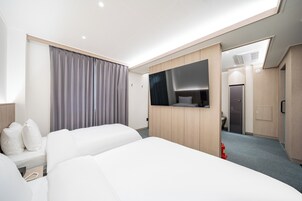 Een hotelkamer met twee bedden, een grote spiegel en een kast.