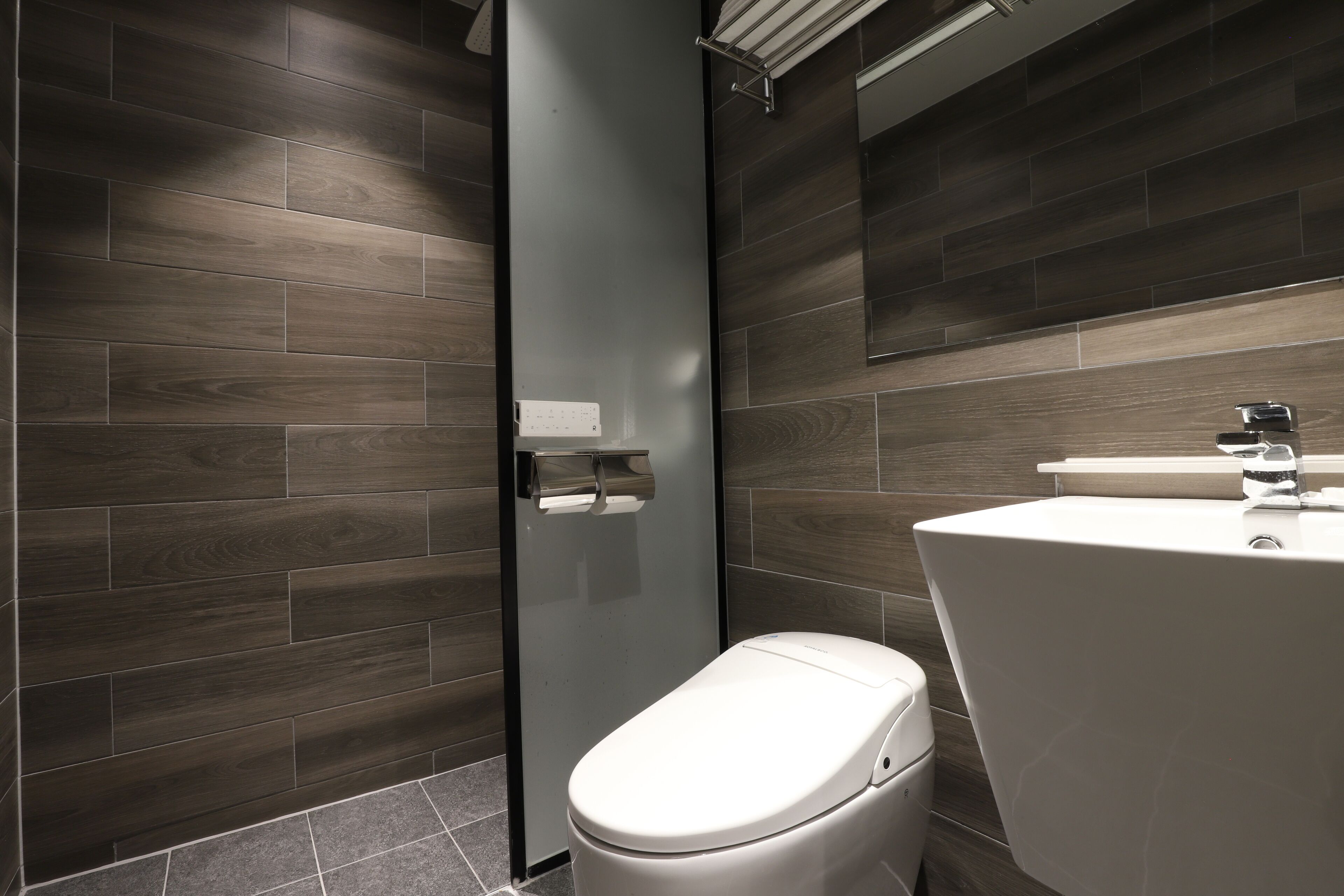 Un baño moderno con inodoro, lavamanos y espejo.