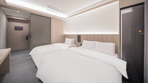 Una habitación de hotel moderna con dos camas, un escritorio y un armario.