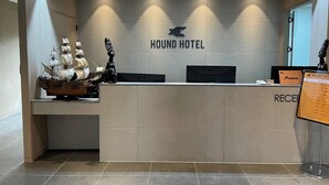 Un mostrador de recepción en Hound Hotel con un modelo de barco y una estatua a la izquierda, y un atril para menús a la derecha.