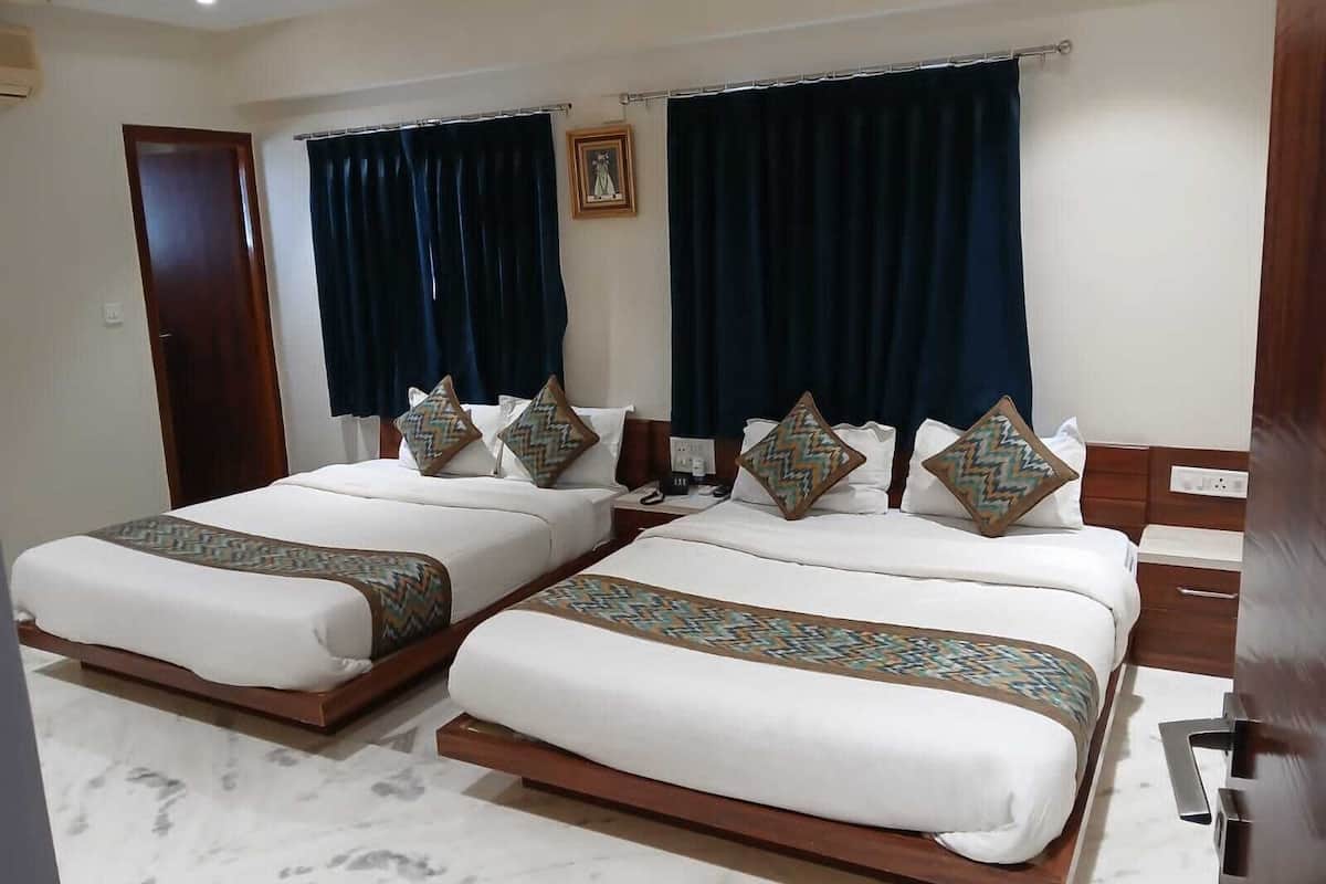 A hotel room with two beds, dark curtains, a framed picture on the wall, and a marble floor.