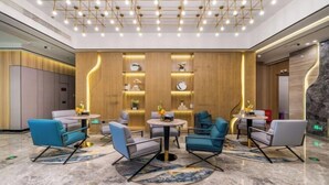 Eine moderne Lobby mit einer zentralen Sitzecke, Holzvertäfelung und einer Decke mit einer Anordnung von Leuchten.