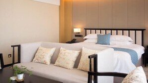 Ein Hotelzimmer mit einem Bett, einer Couch, einem Nachttisch und einer Lampe.
