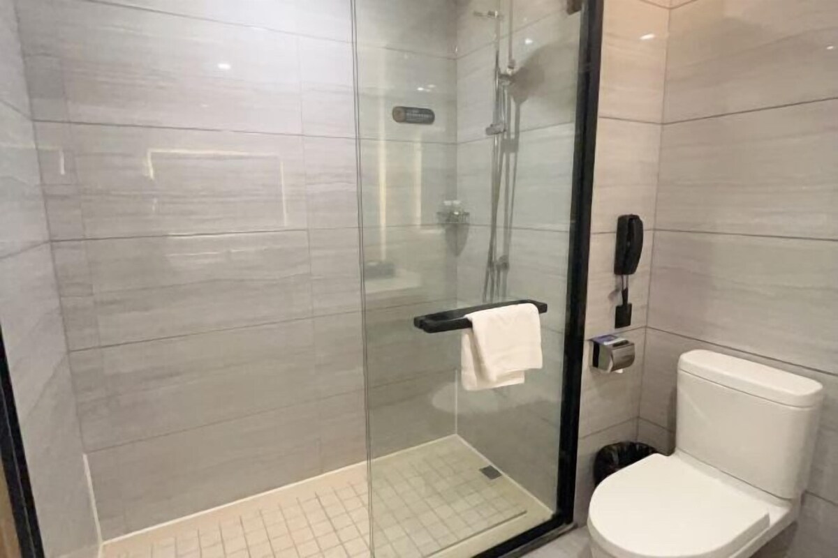 A modern bathroom with a glass-enclosed shower, a toilet, and a telephone.
