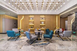 A modern lobby with seating arrangements, a reception desk, and a decorative wall with clocks. - Yurong International Hotel (Kunshan)