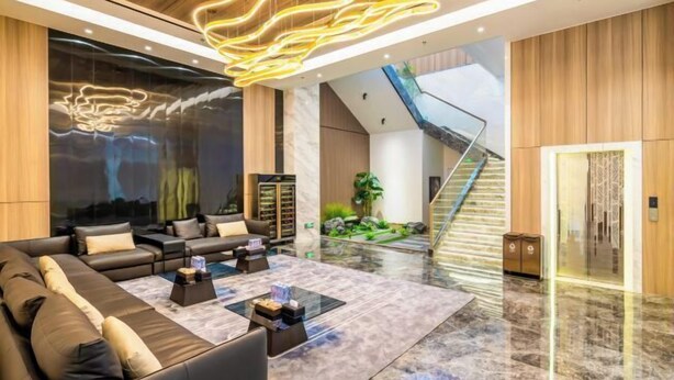 Eine moderne Lobby mit einer Ledersofa, einem Glastisch und einer Treppe zu einer oberen Etage.