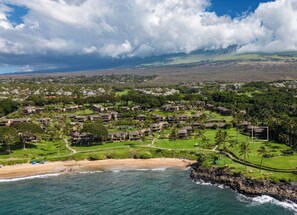 Eine Luftaufnahme eines Küstenresorts mit mehreren Gebäuden, einem Strand und einer felsigen Küstenlinie.