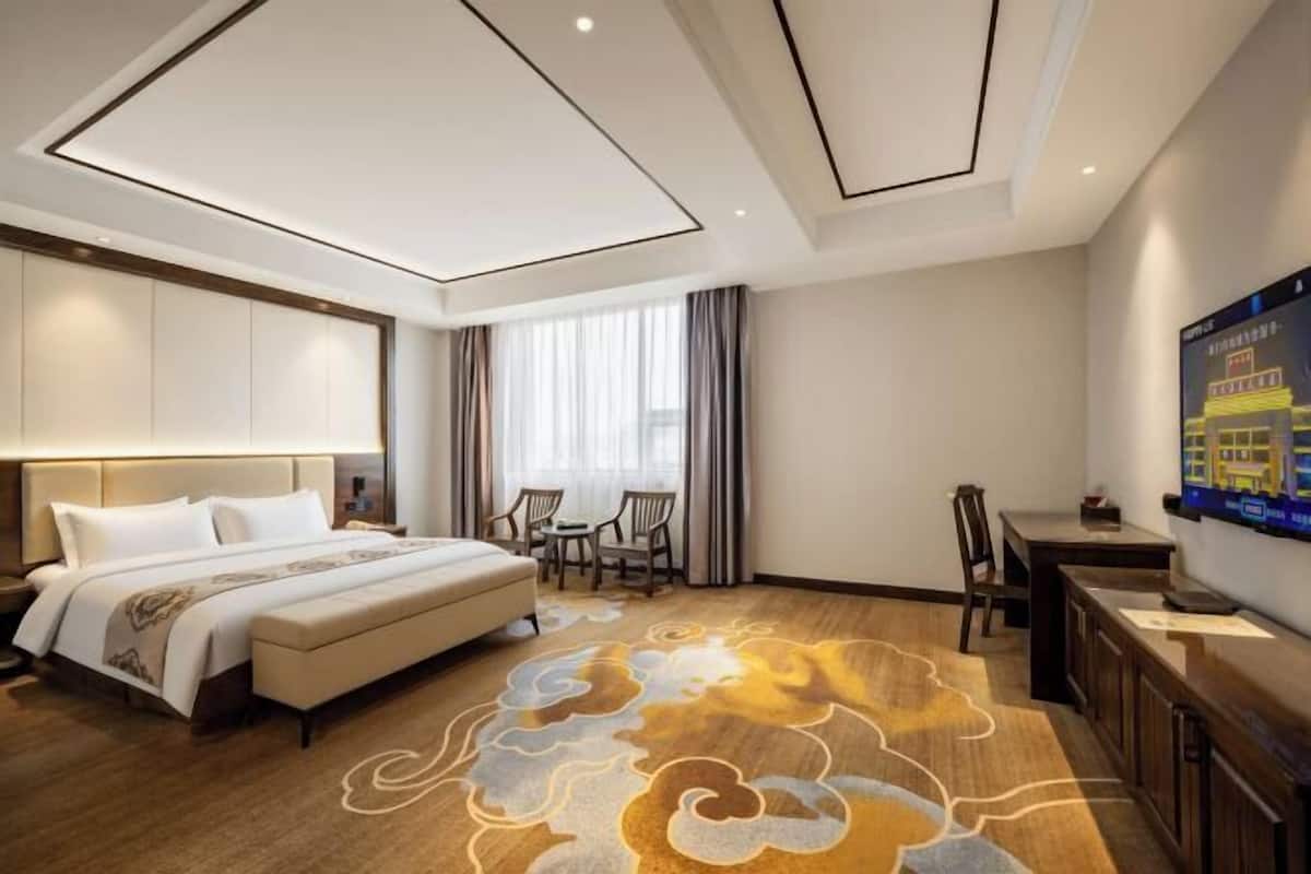 Habitación de hotel con una cama grande, un escritorio, una silla y un televisor.