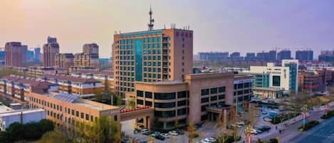 A modern urban area with a prominent multi-story building featuring a central tower with a satellite dish.