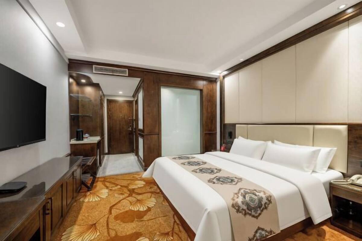 Una habitación de hotel con cama, televisión, escritorio y armario.