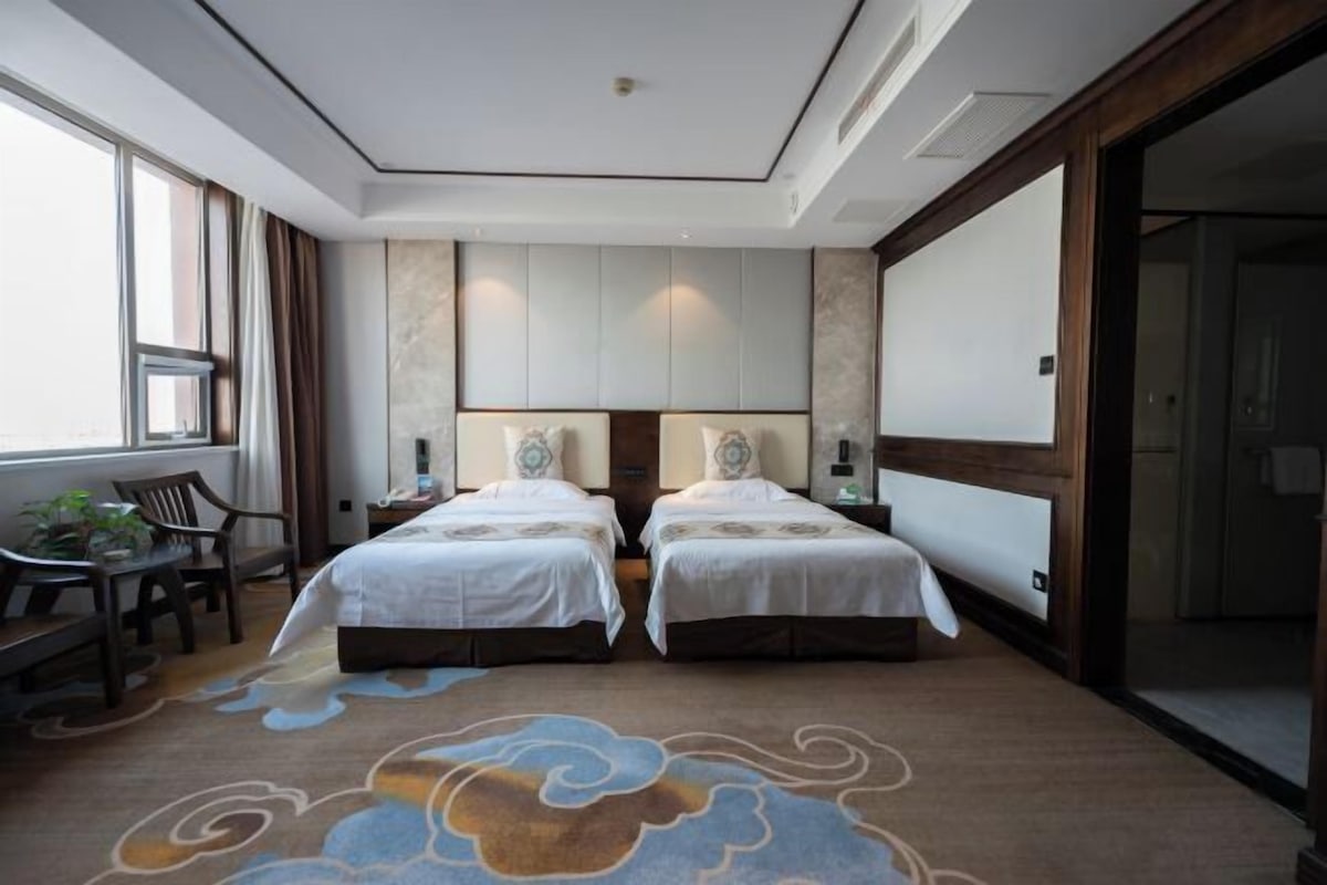 A hotel room with two beds, a desk, and a chair.