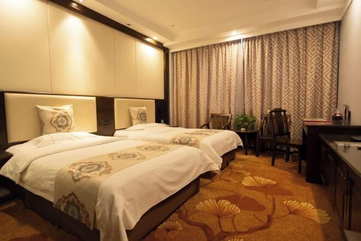 Habitación de hotel con dos camas, un escritorio, una silla y una alfombra estampada.