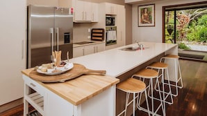 Et moderne køkken med en stor ø, rustfrie stålapparater og udsigt til grønne områder.