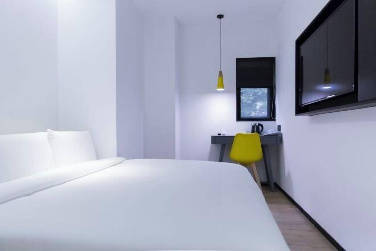 Un dormitorio moderno con cama, escritorio, silla y ventana.