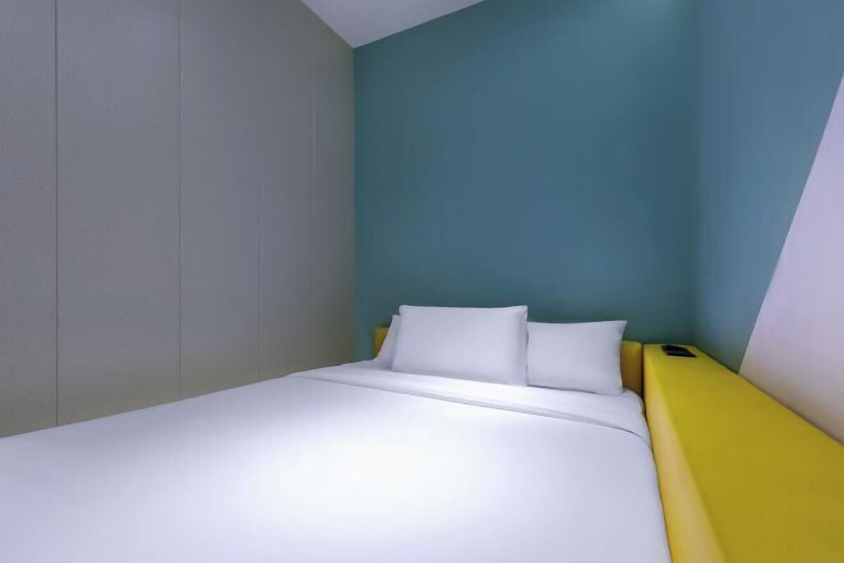 Una camera con un letto, una testiera gialla e una parete verde acqua.