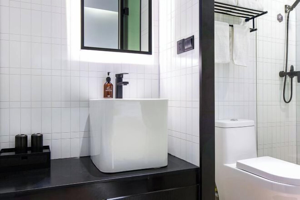 Un bagno moderno con lavandino bianco, specchio e zona doccia.