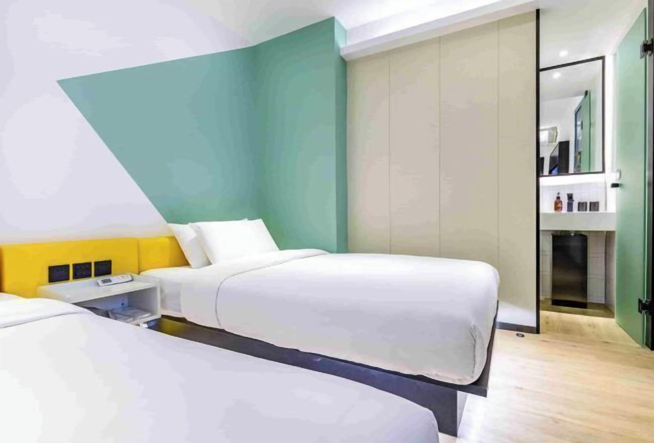 Una habitación de hotel con dos camas, una mesita de noche, un espejo y un armario.