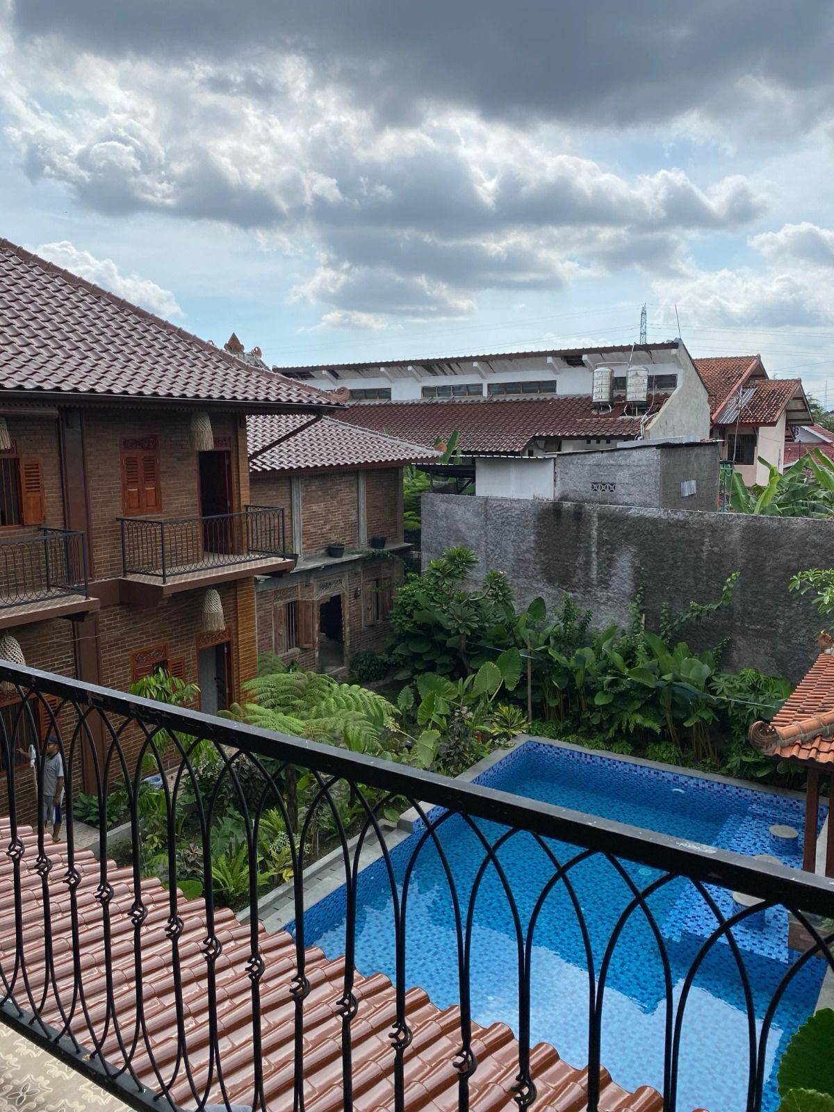 A residential area with a swimming pool, brick houses, and lush greenery.