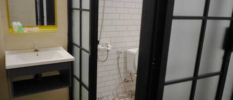 A bathroom with a white sink, mirror, and toilet. The floor has patterned tiles, and there is a shower area visible through a glass door.
