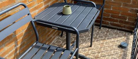 Un patio con pared de ladrillo, puerta de madera y mesa con dos sillas.