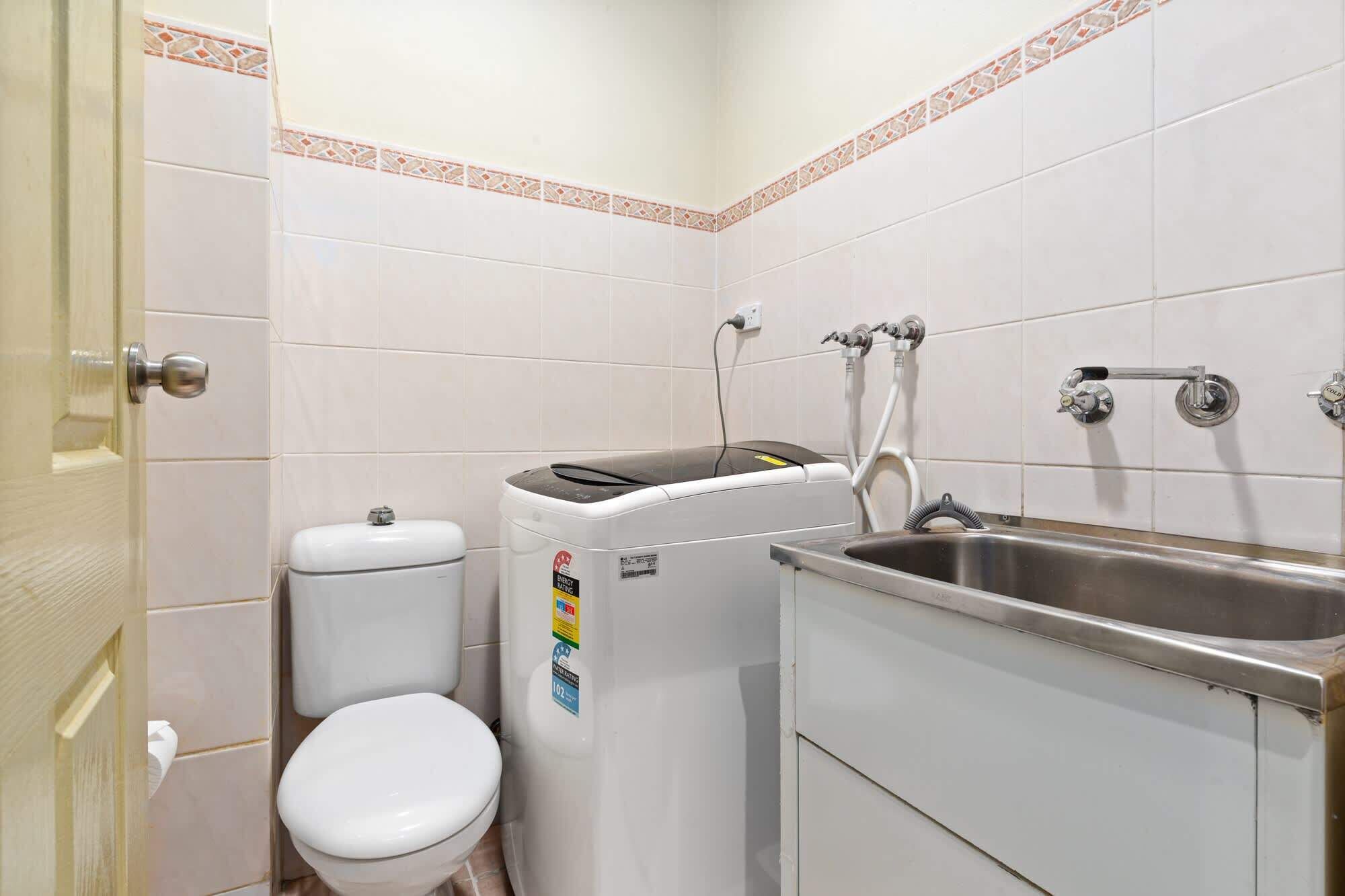 A small bathroom with a toilet, a washing machine, and a sink.
