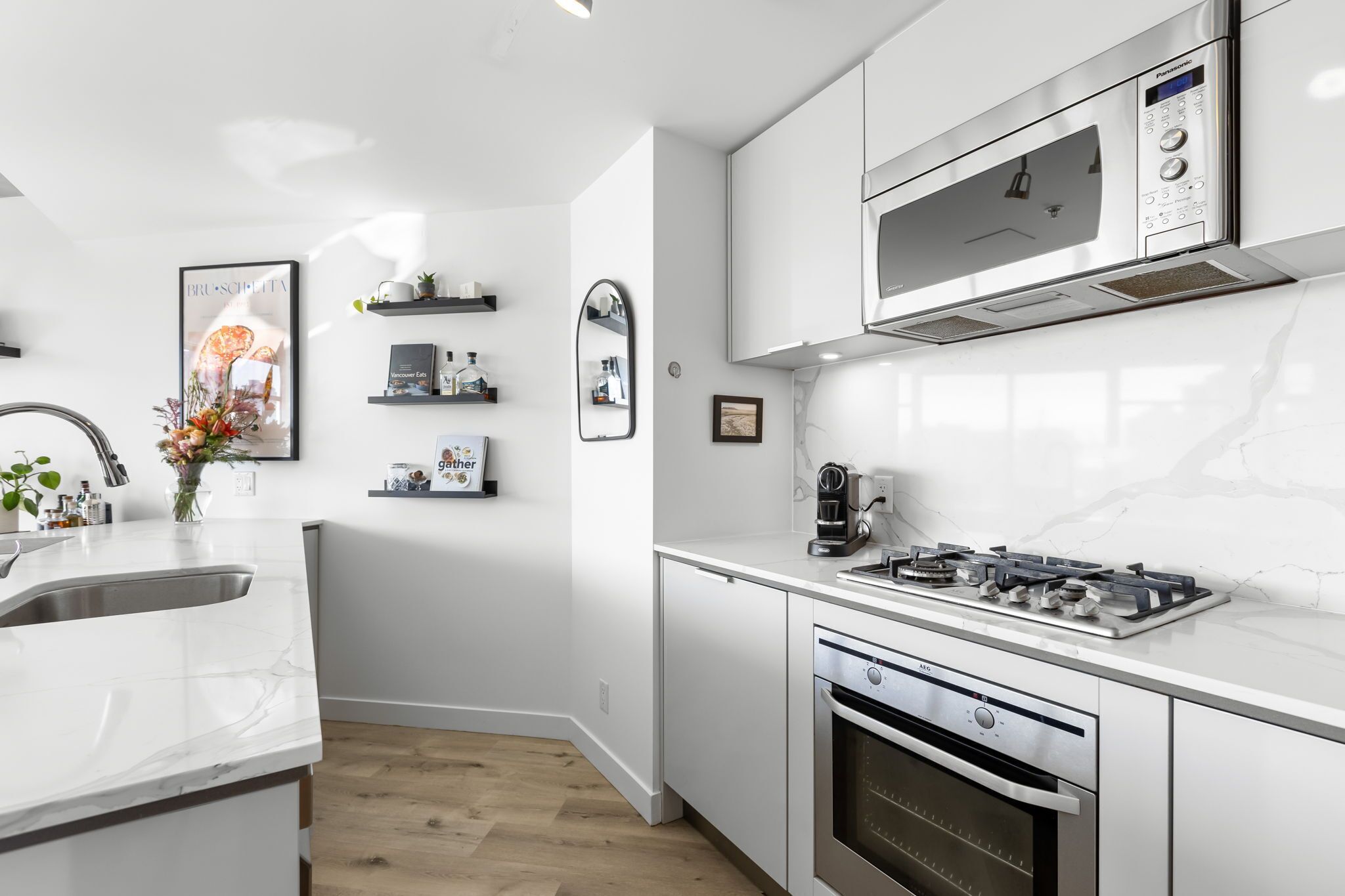 Een moderne keuken met witte kasten, een ingebouwde oven, een gasfornuis en een magnetron.