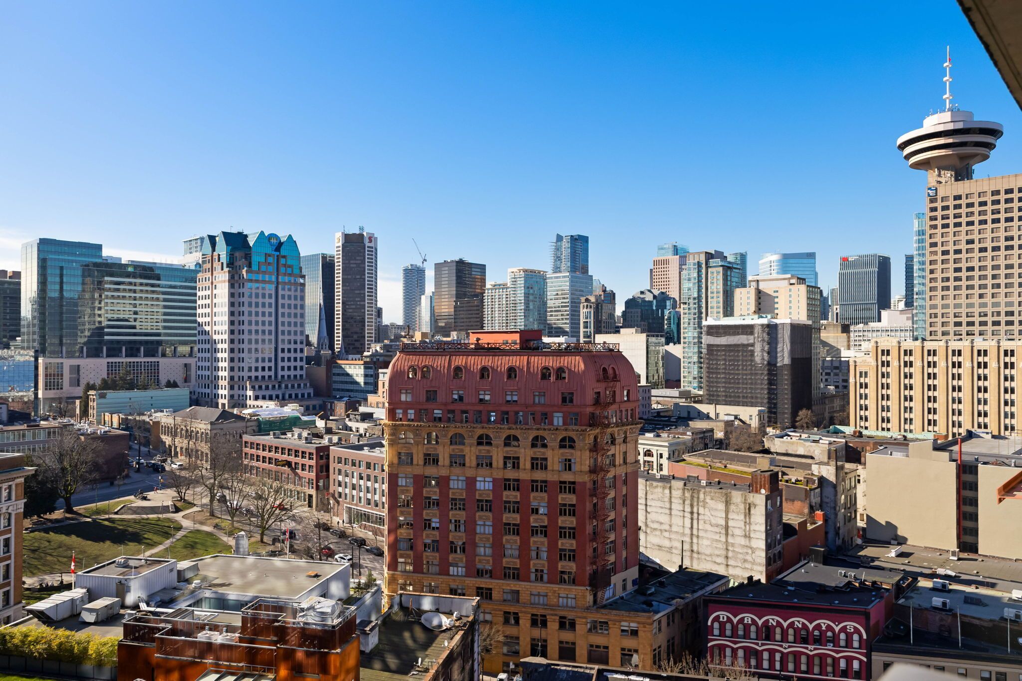 A cityscape with a mix of modern and historic buildings, including a prominent red building with arched windows and a dome.