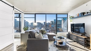 A modern living room with a large window, a sofa, a coffee table, and a TV.