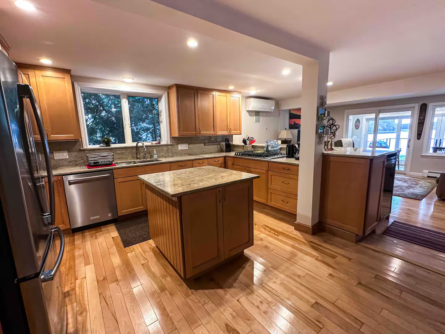 A modern kitchen with wooden cabinets, a stainless steel refrigerator, and a large island.