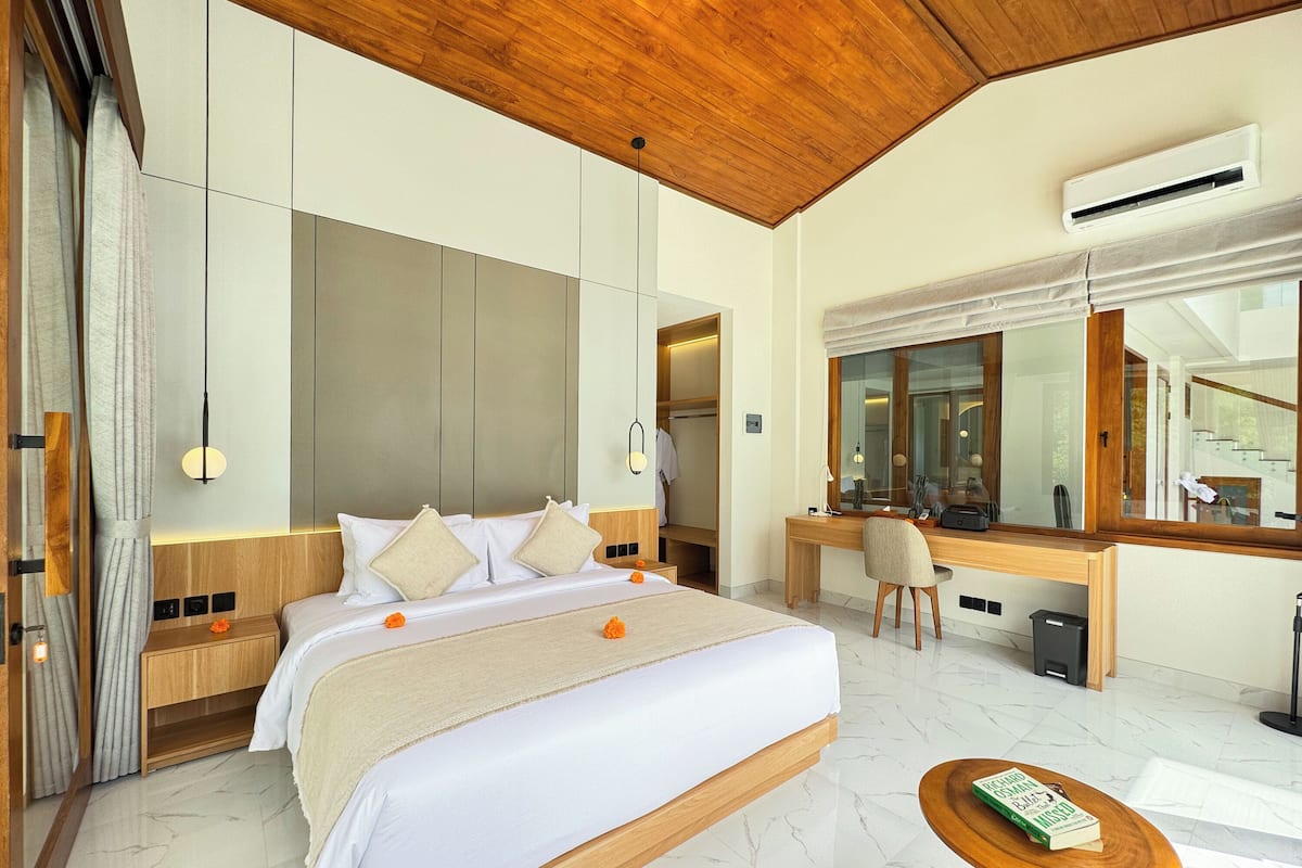 A modern hotel room with a large bed, a desk, and a mirror.