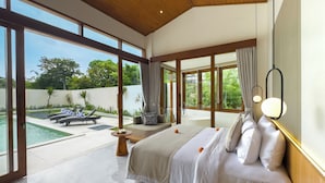 A spacious bedroom with a large bed, a view of the pool, and a balcony.