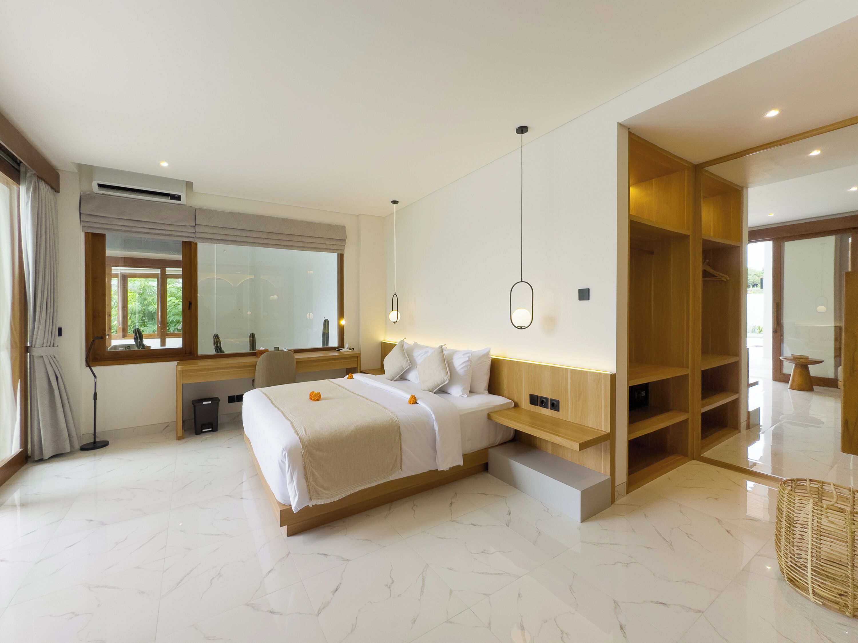 A modern bedroom with a large bed, a desk, and a walk-in closet.